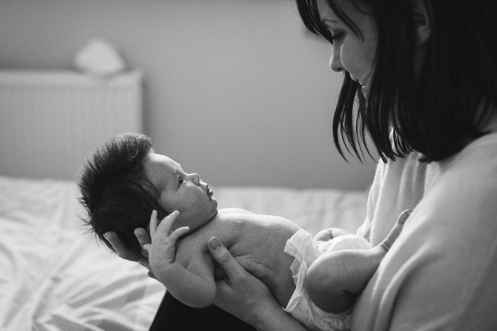 Tender moment between parent and newborn in soft natural light.