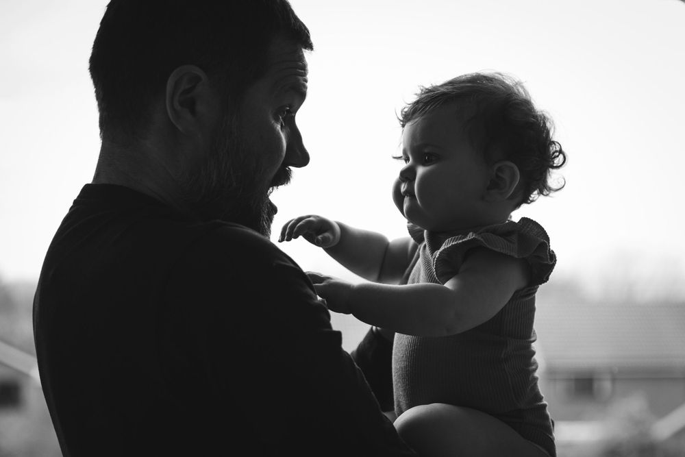 A black and white silhouette of a parent holding their baby in a tender moment.