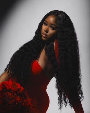 Dramatic portrait in red dress with long flowing dark hair against light background.