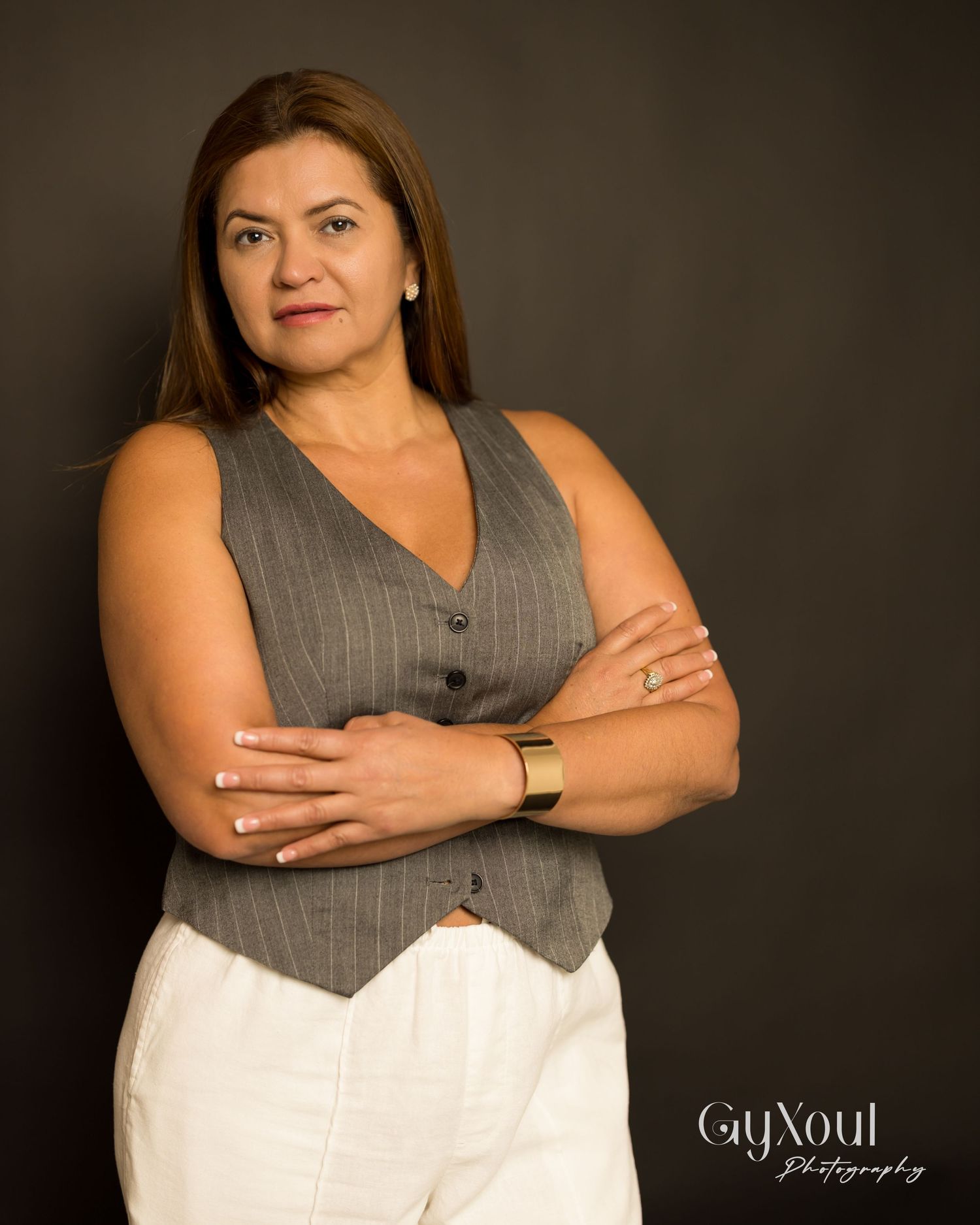 Studio portrait of a professional wearing a gray vest against a dark background.