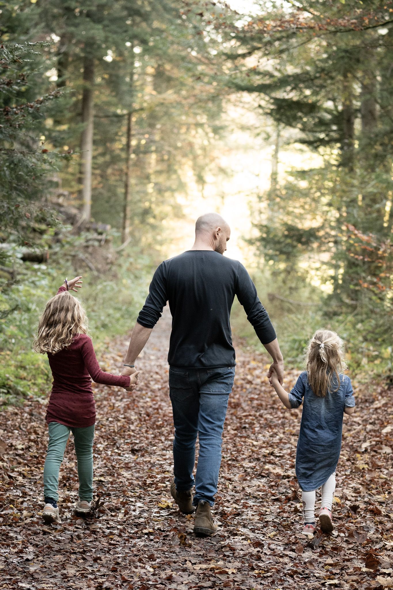 Vater spaziert mit Töchtern durch den Wald