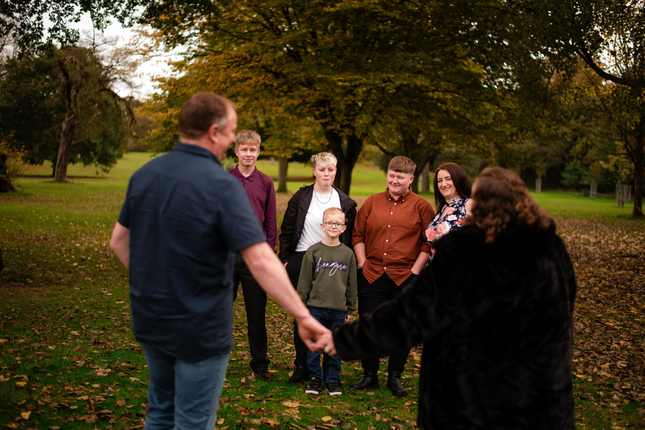 Candid moment of family members laughing together in a park during autumn.