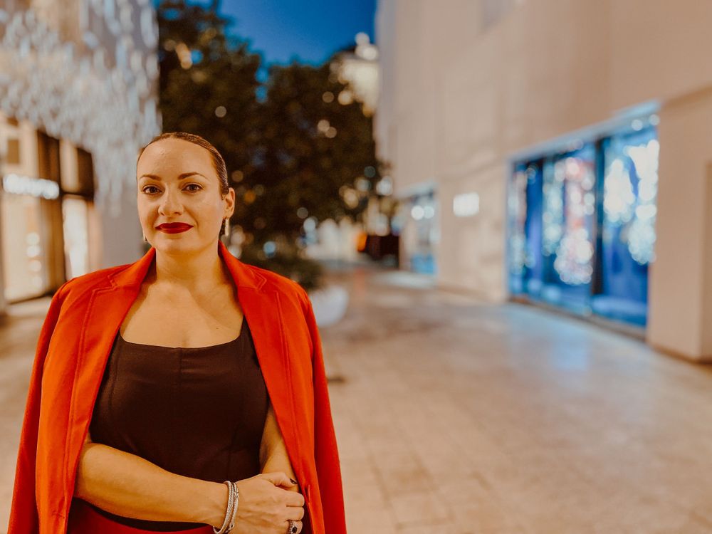 Person in vibrant red jacket standing on illuminated street at night.