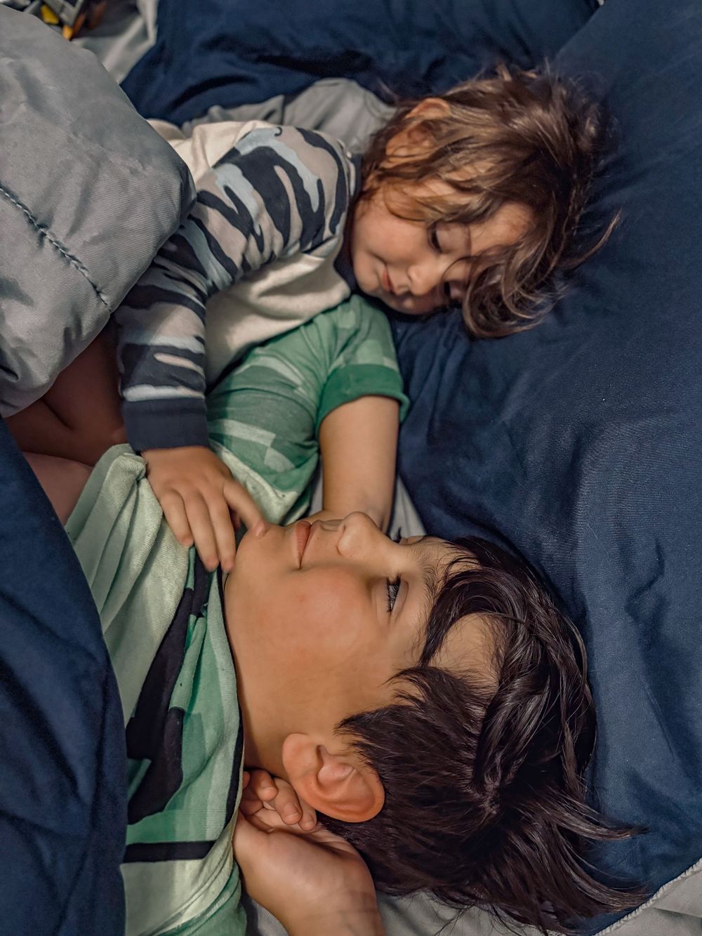 Two people sharing a tender moment while resting on blue bedding.