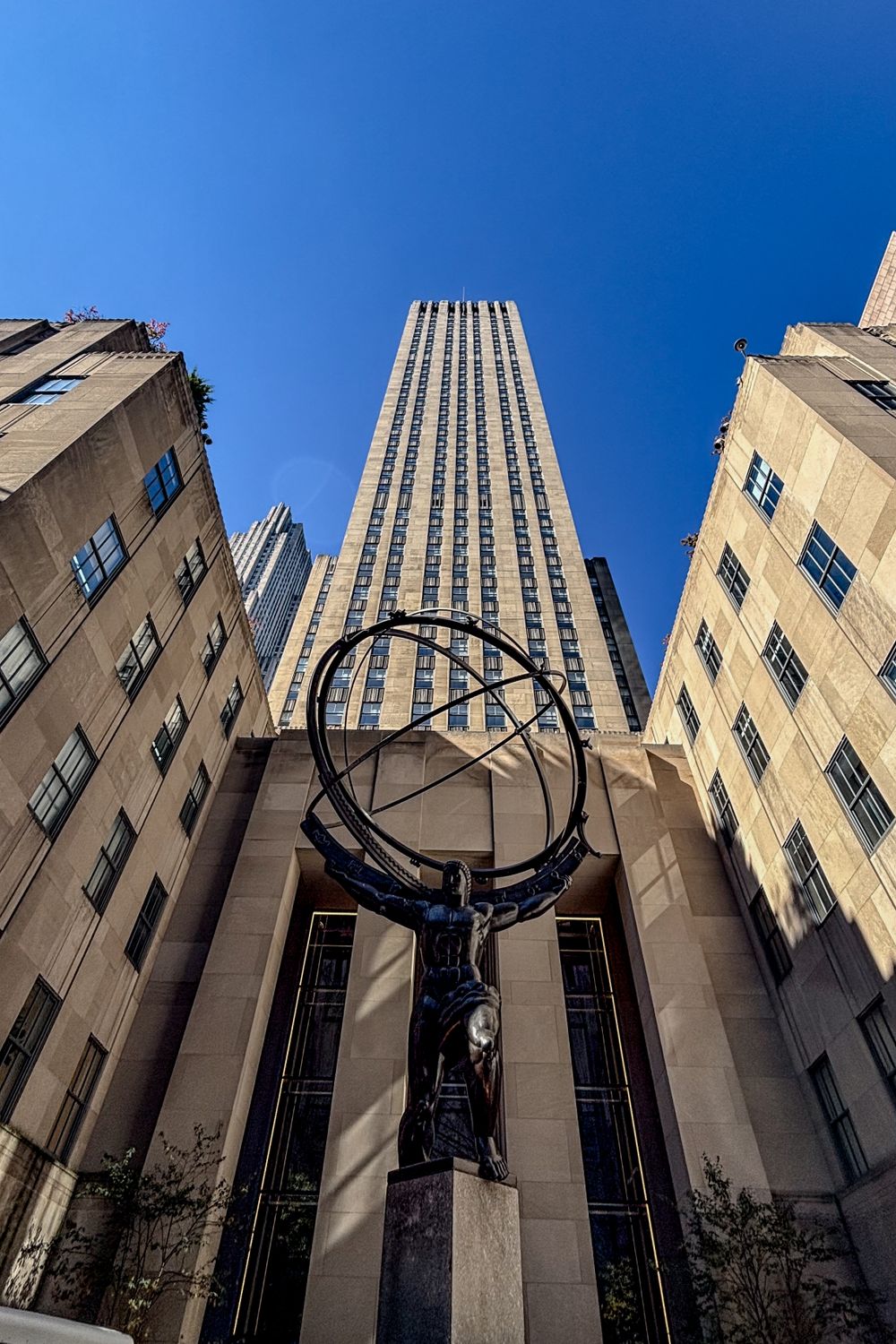 Atlas statue stands in front of Rockefeller Center with towering skyscraper behind it.