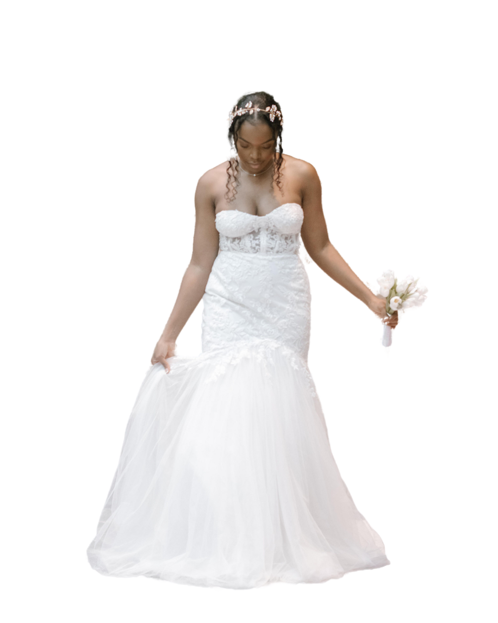 A bride in a strapless white mermaid wedding gown stands elegantly while holding flowers against a white background.