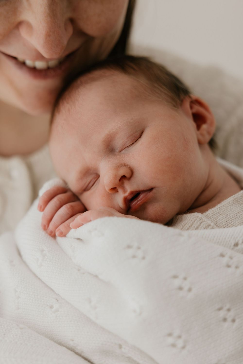 Slapend newborn baby’tje in mama's armen in zachte deken in rustige studio