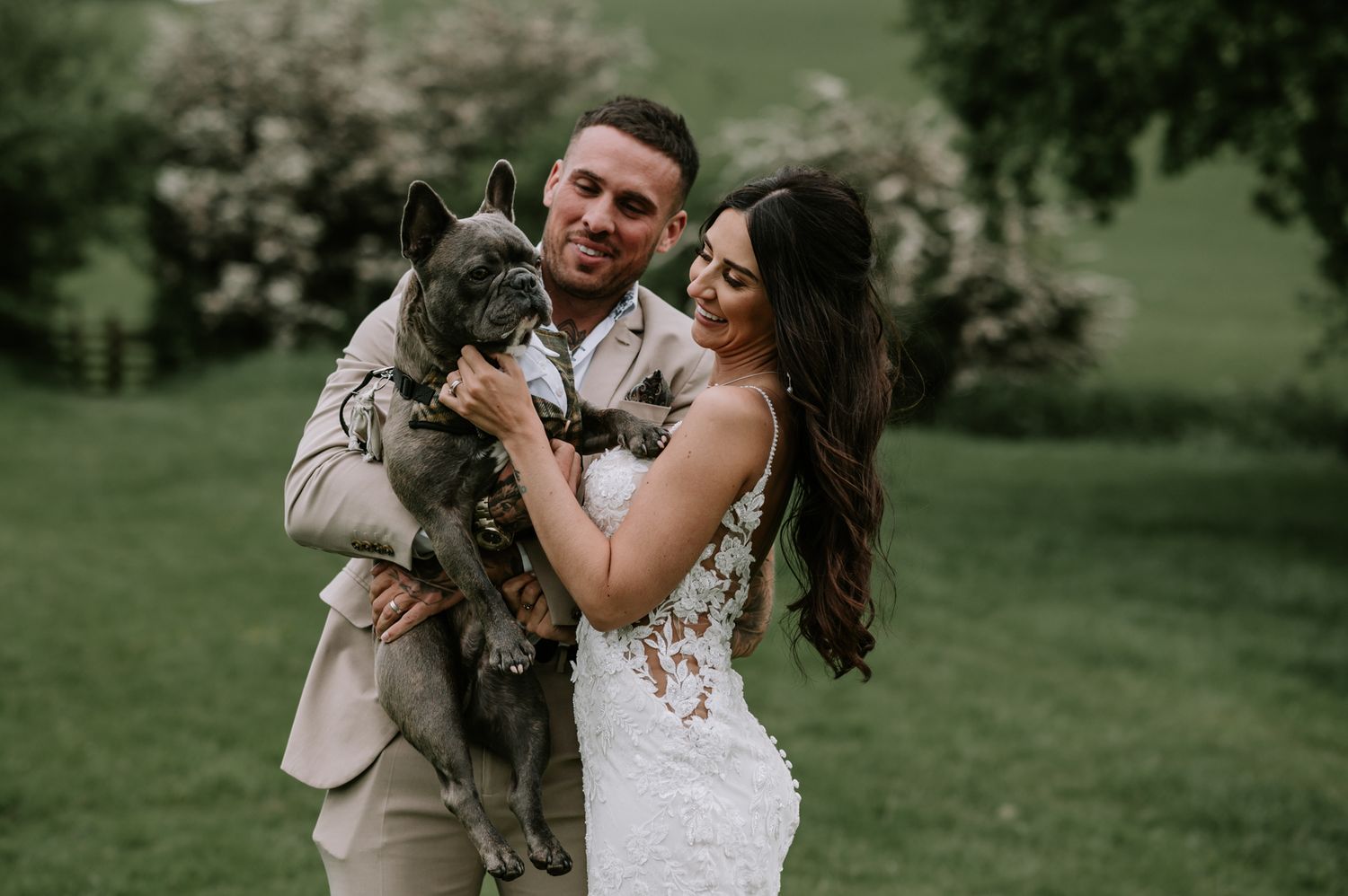 Newlyweds walk together through a quaint village courtyard surrounded by well-wishers and historic brick buildings.
