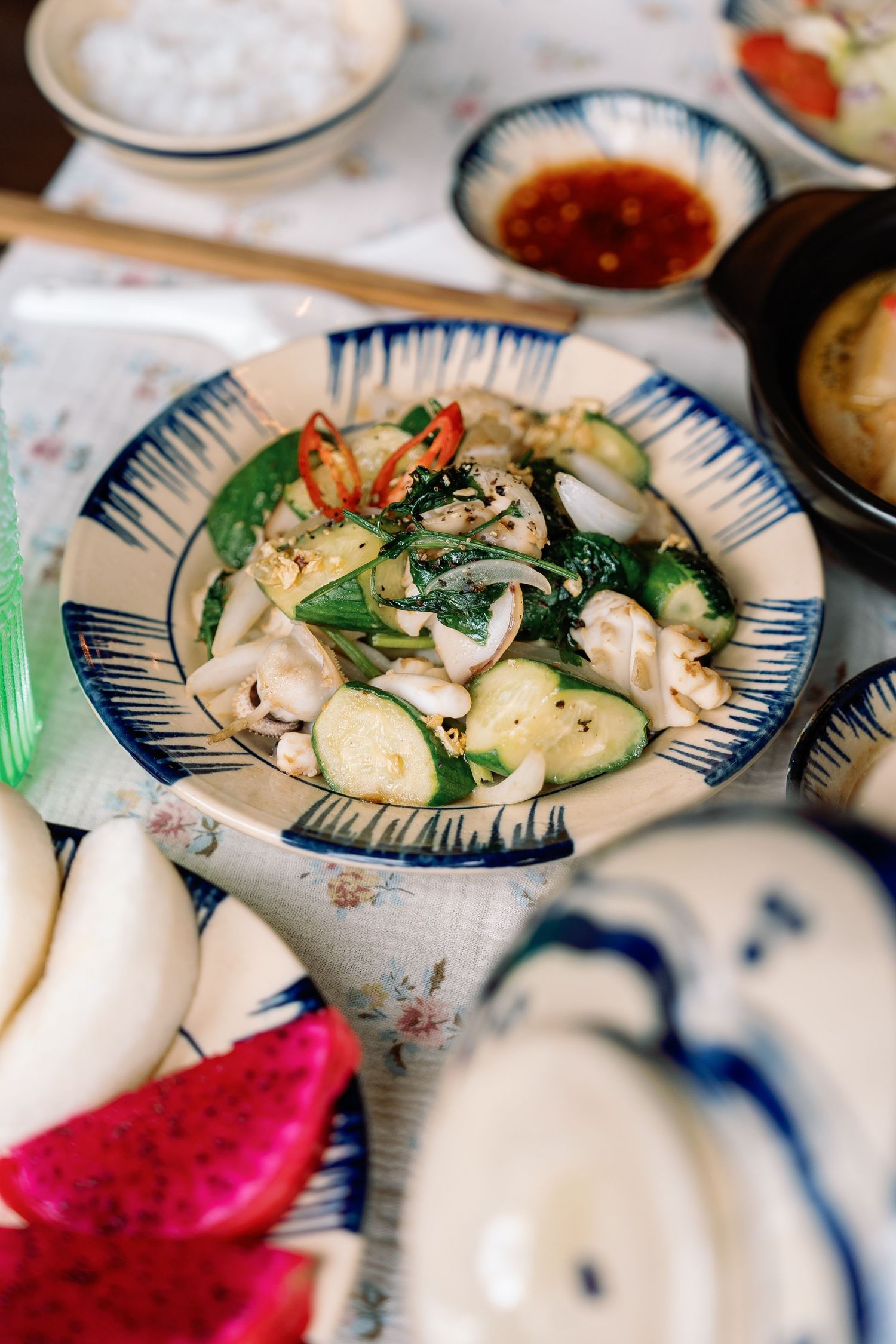 Asian stir-fried seafood dish with shrimp, mushrooms and bok choy served in blue and white ceramic bowl with side dishes.
