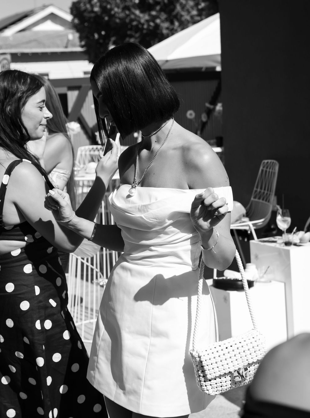 Black and white candid photographs show party guests in polka dot and white dresses mingling at an outdoor event.