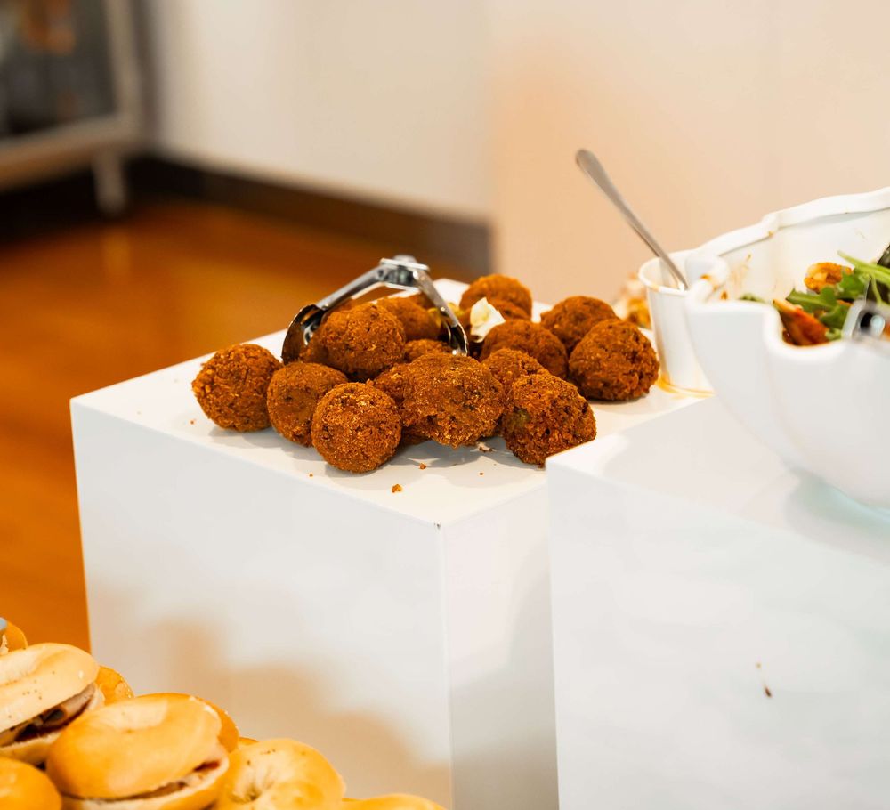 Small brown deep-fried croquettes arranged on a white serving plate against a warm wooden surface.