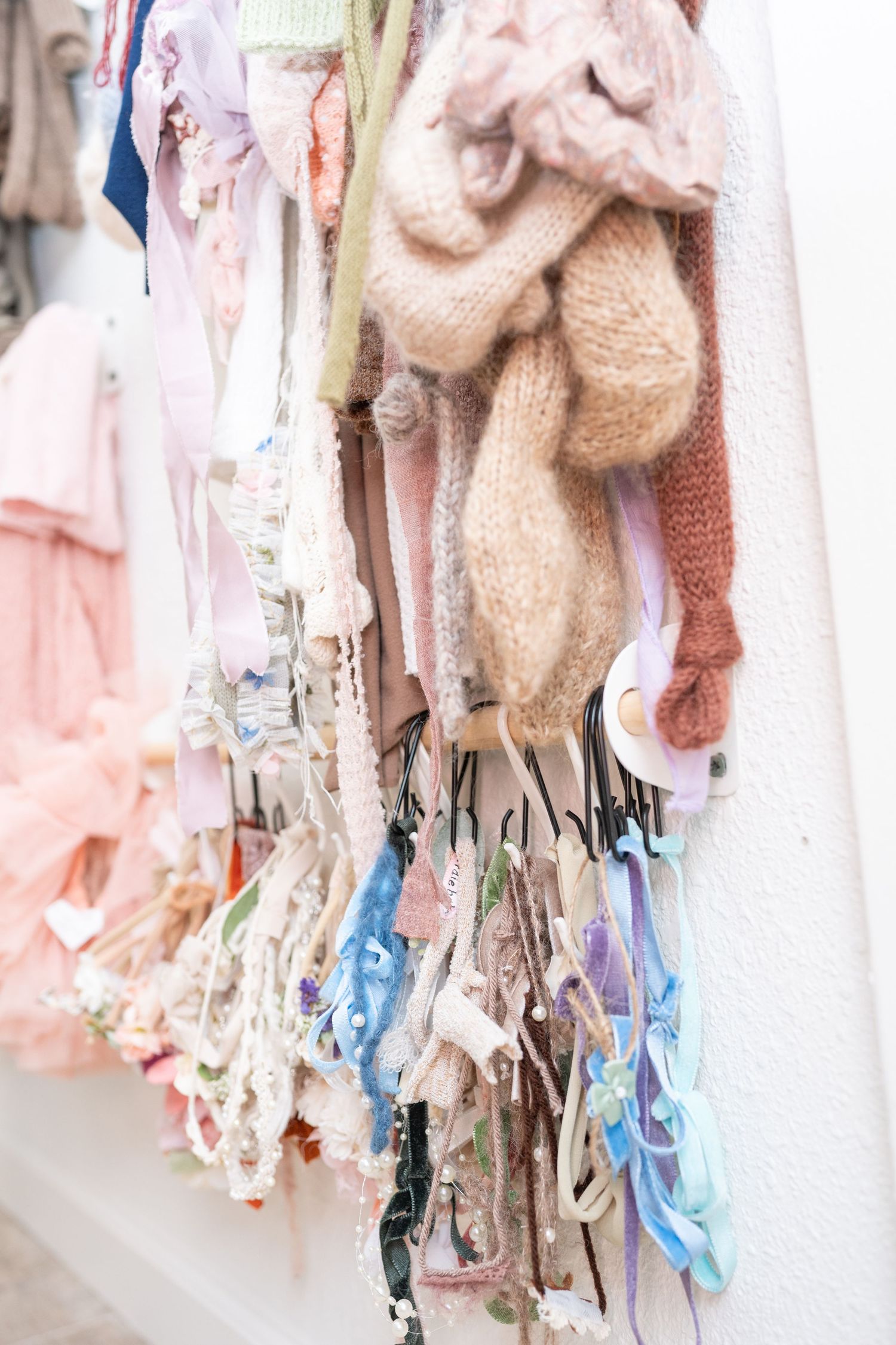 Soft pink and beige clothing items with delicate textures displayed on retail hangers.