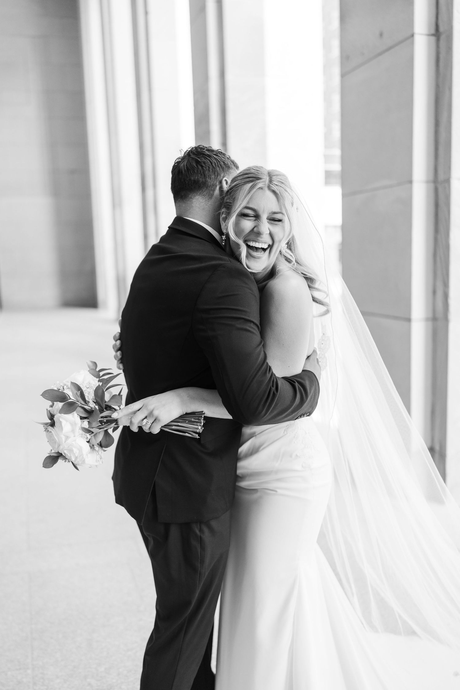 Candid moments of laughter and embraces between columns at a wedding. Grand Rapids Michigan