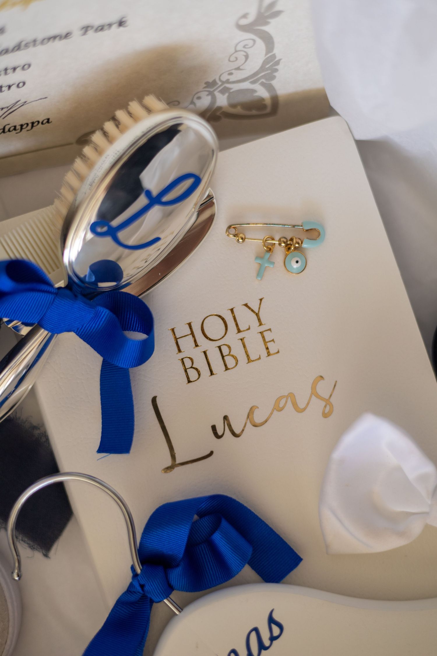 Holy Bible with decorative blue ribbons and a delicate gold bracelet charm displayed on a white surface.