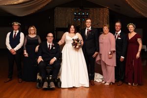 Wedding guests and family members pose together for formal portraits in an indoor venue.