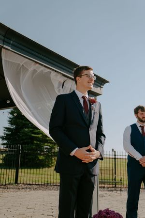 Wedding ceremony setup with white draping and evergreen trees in the background.