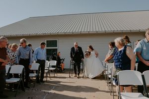 Outdoor wedding reception setup with chairs and tables under bright sunlight.