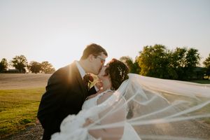 Bride and groom share tender moment on outdoor path during sunset photo session.