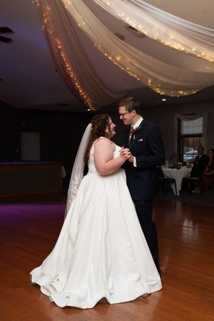 Couple shares first dance under twinkling lights in elegant reception venue.