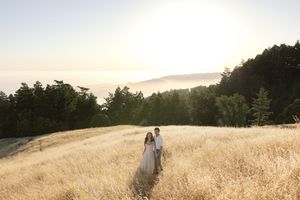 Ethereal sunset scene with figures walking through a sunlit hillside meadow.