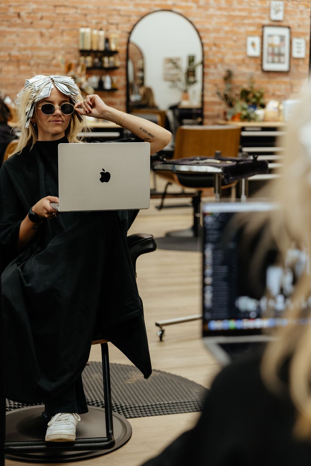 A series of candid shots in a salon showing someone in a black top getting their hair styled and laughing.