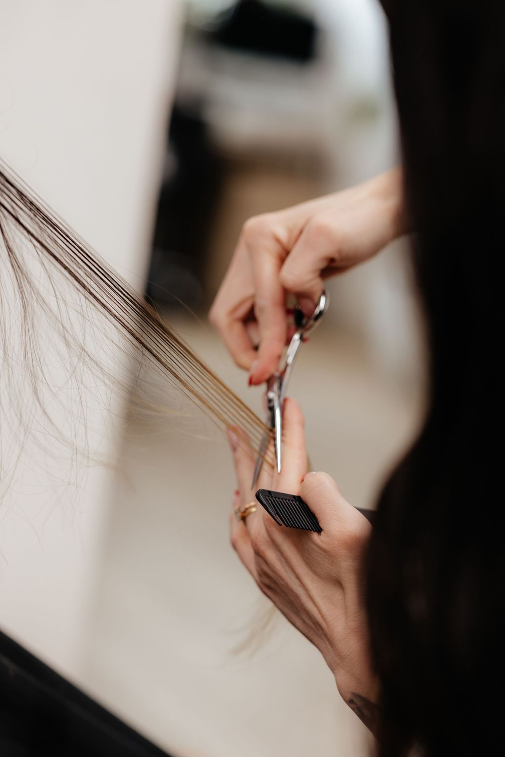 Closeup of hairdresser's hands cutting hair with professional scissors in a salon.