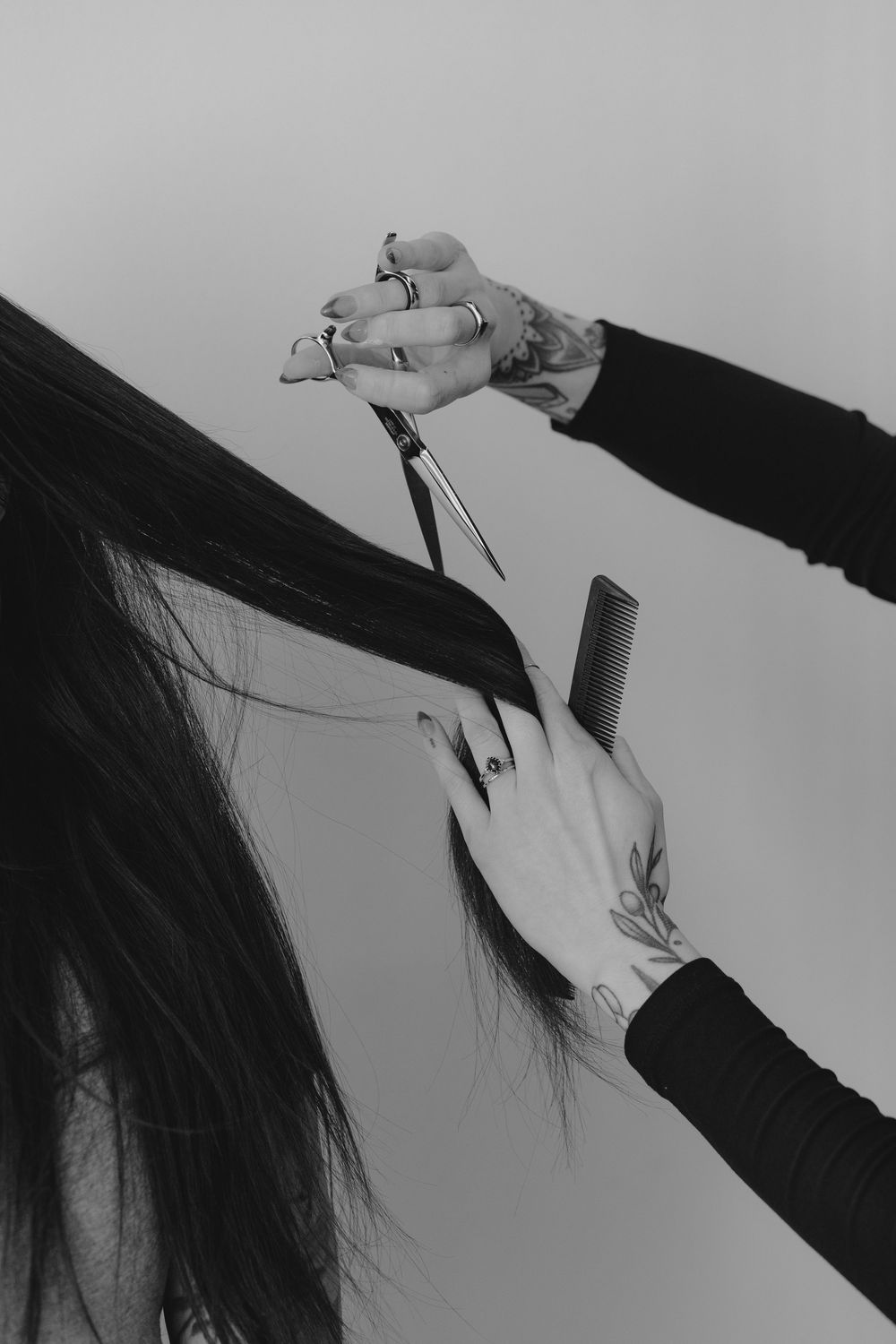 Black and white photo of hands styling hair with scissors and comb during a haircut.