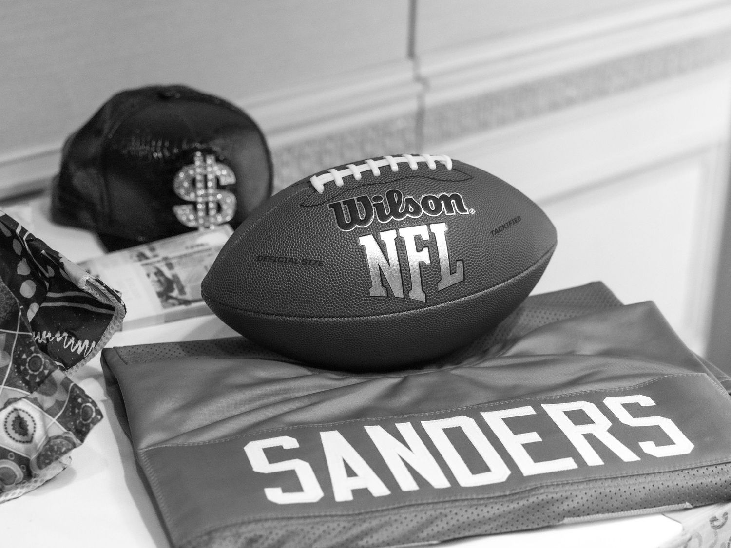 Props for a photo booth are displayed on a table including an NFL football and Barry Sanders jersey and a leather hat with large dollar sign