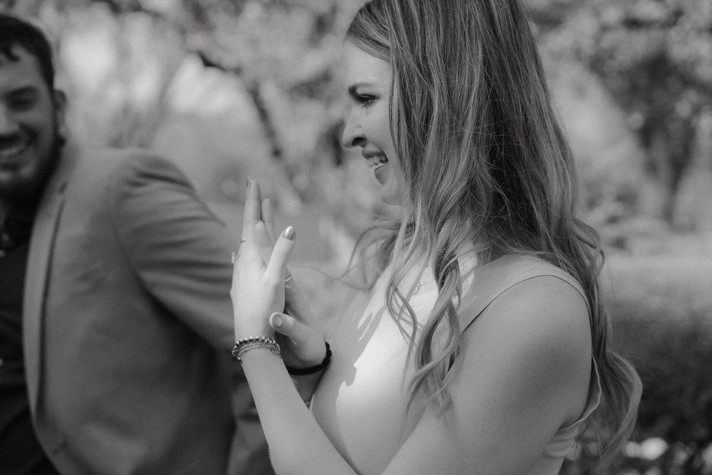 Black and white candid moment showing joyful laughter outdoors during a casual summer gathering.