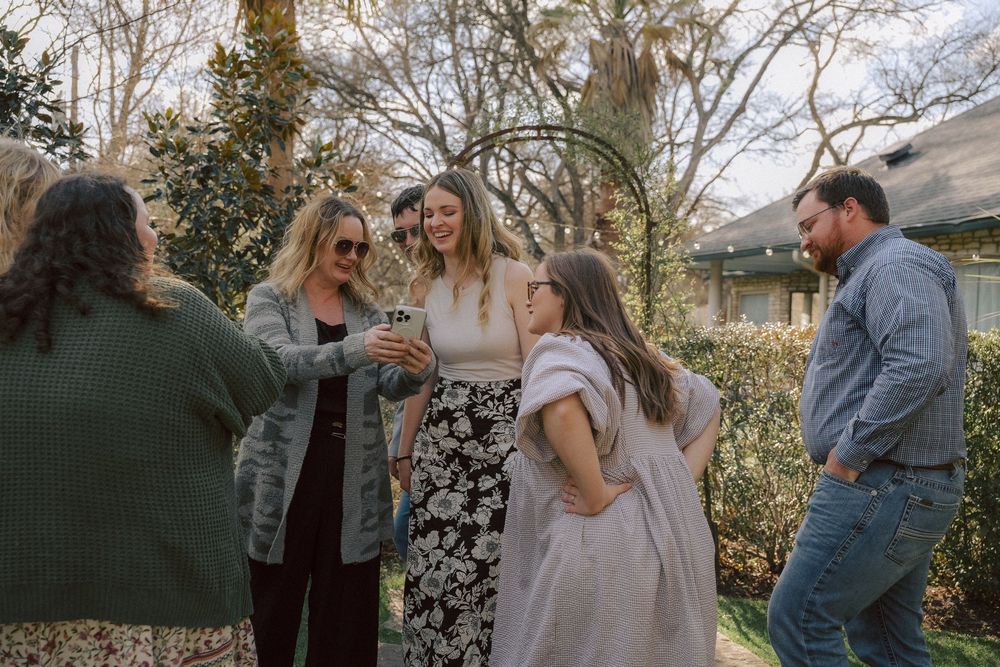 A group of friends gather outdoors in a casual setting during a backyard social gathering in natural lighting.