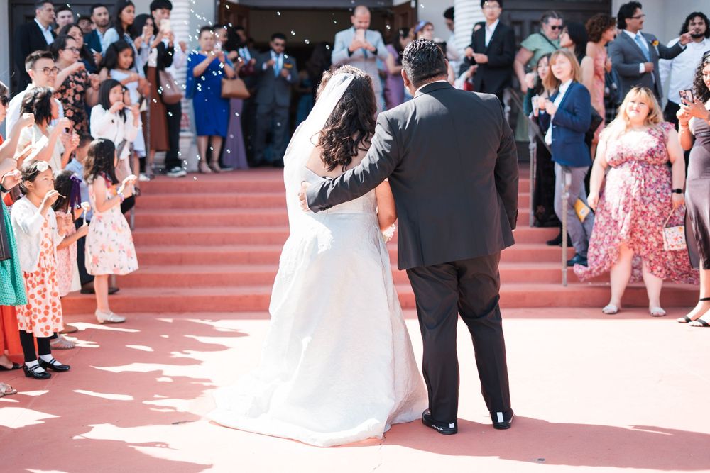 Husband and wife look at all the people in their wedding and smile