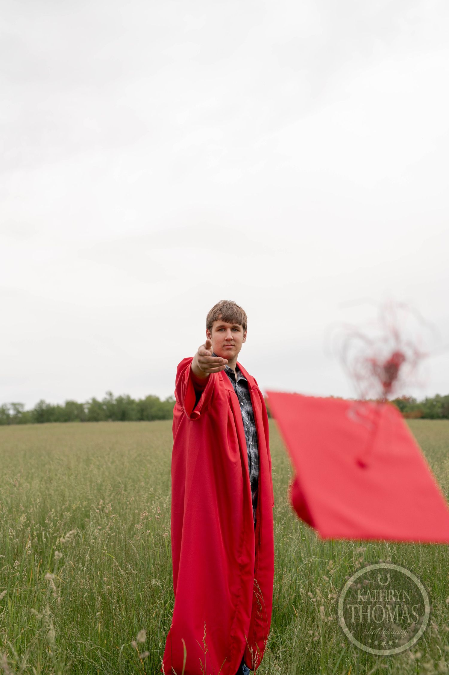 A red blanket waves dramatically in a lush green field against a cloudy sky.