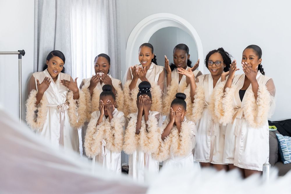 Group in matching beige robes and slippers stand together making silly faces for a fun candid photo.