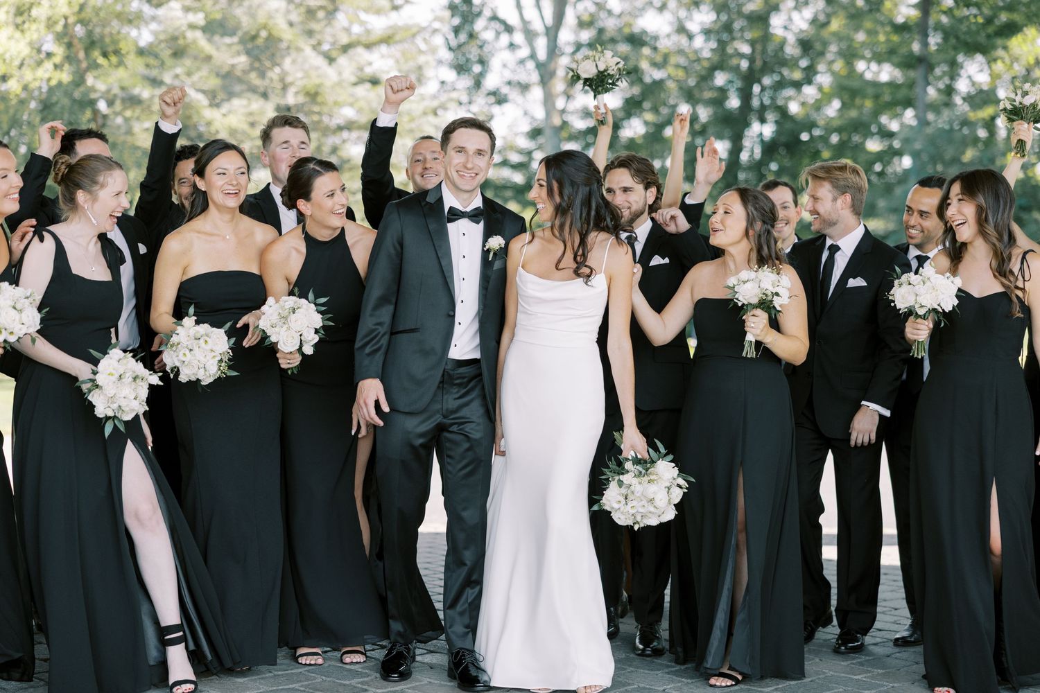 Wedding party members dressed in black and white formal attire pose together outdoors in multiple group photos.