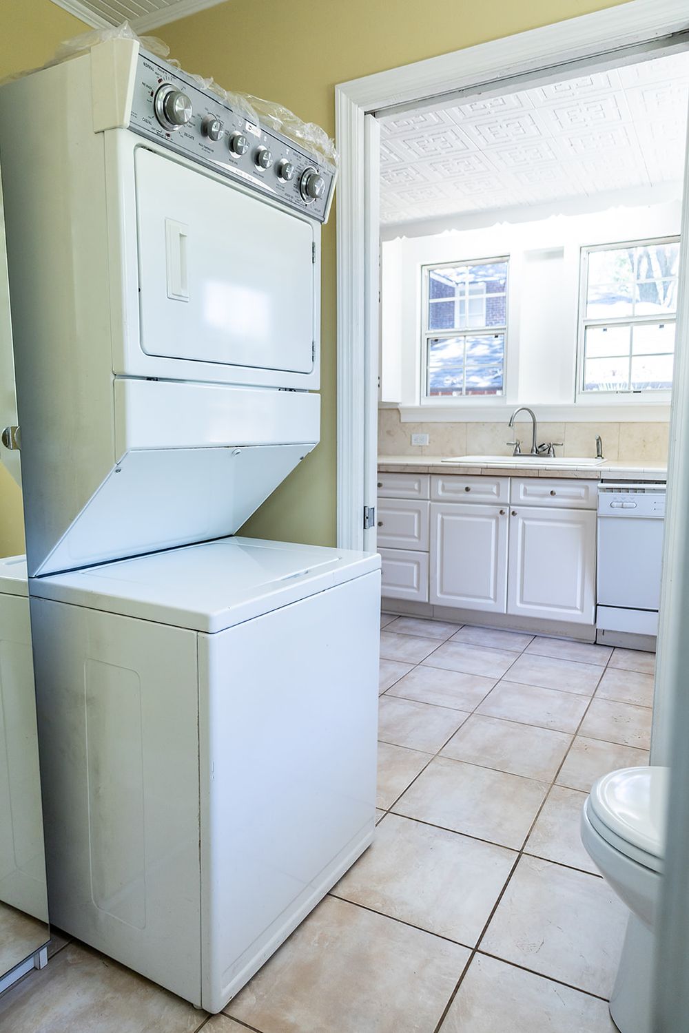 Four views of a bright laundry room with white appliances, cream tile flooring, and pale green walls.