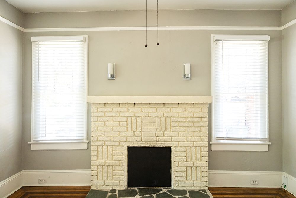 Modern living room featuring neutral beige walls, white trim, and multiple windows with horizontal blinds.