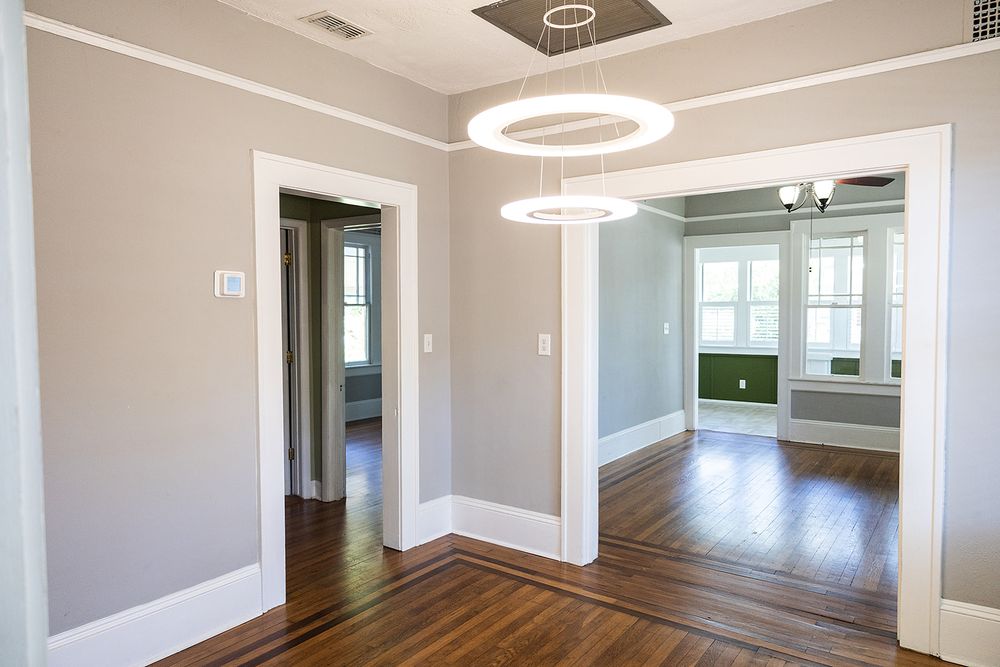 Modern home interior hallway with white trim, gray walls, hardwood floors, and circular ceiling lights.