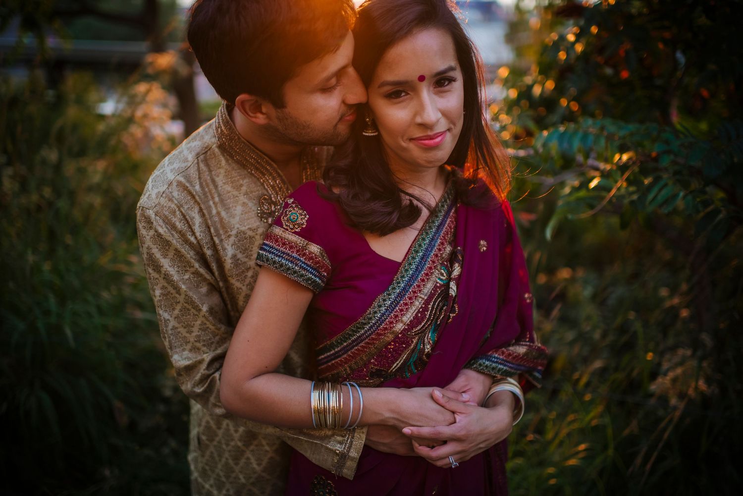 Romantic couple in traditional Indian attire embracing during golden hour.