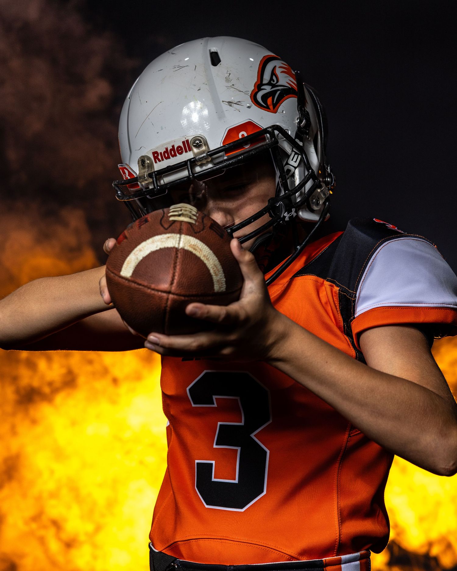 Football player in orange jersey photographed with dramatic fire effects.