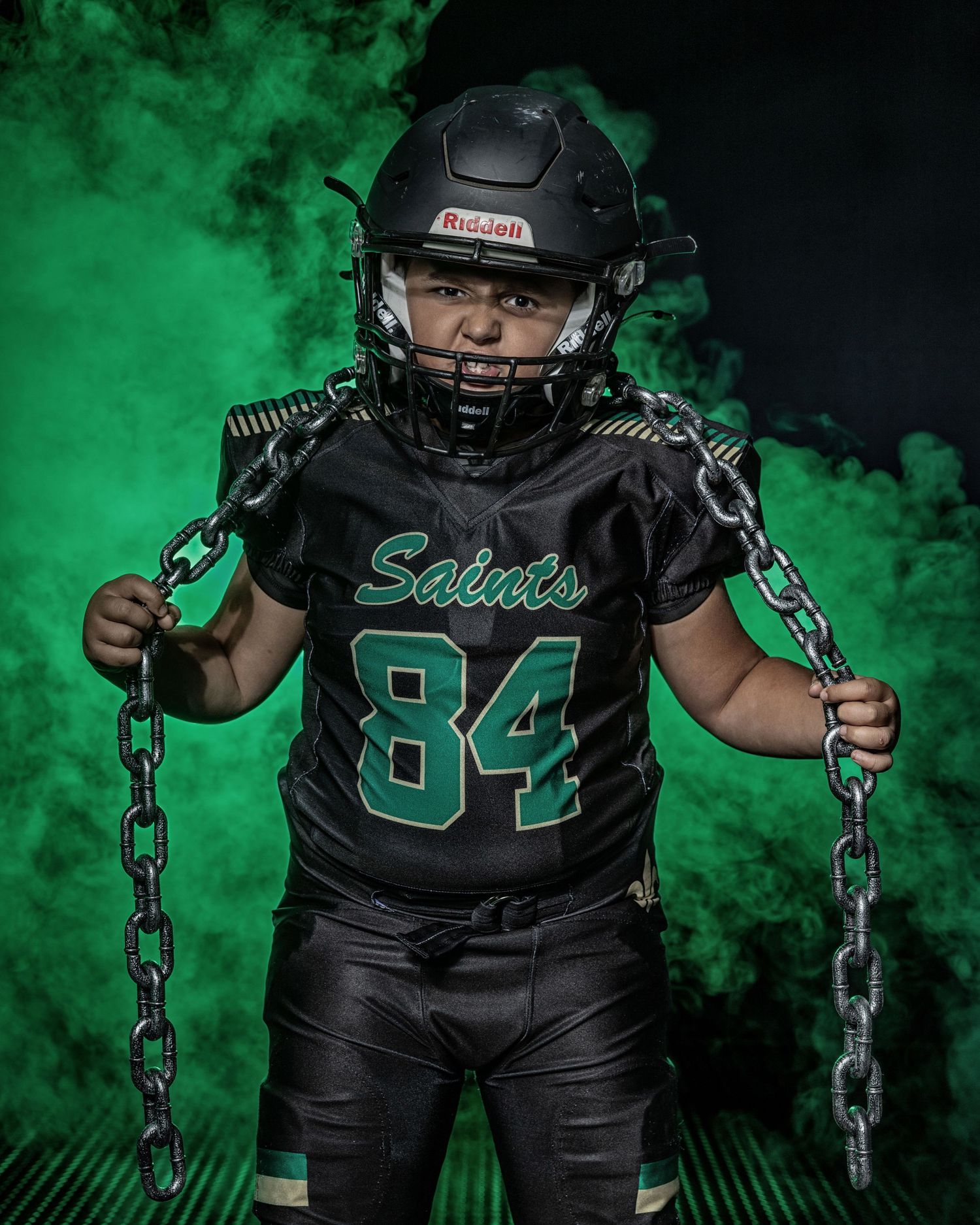 Dramatic sports portrait of football player in black uniform with green smoke effects.
