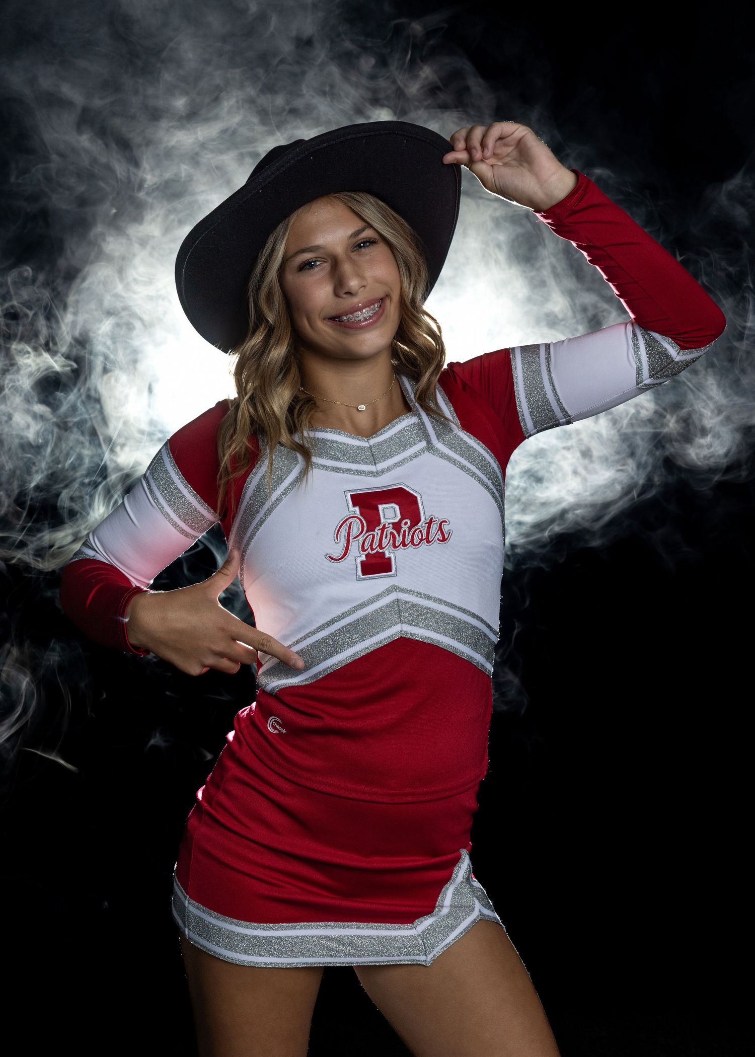 Cheerleader in red and white uniform poses with dramatic smoke effects.