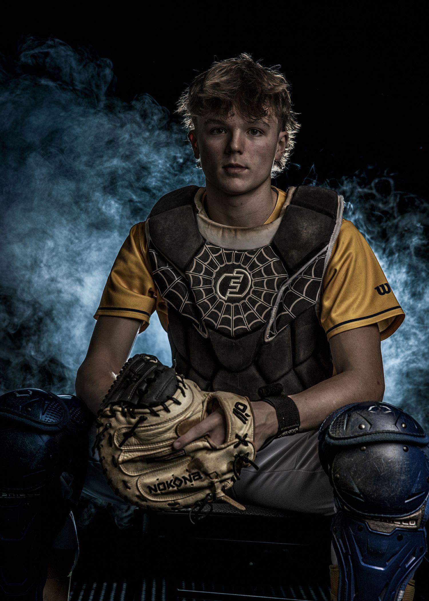 Dark moody sports portrait with baseball equipment and dramatic smoke effects.