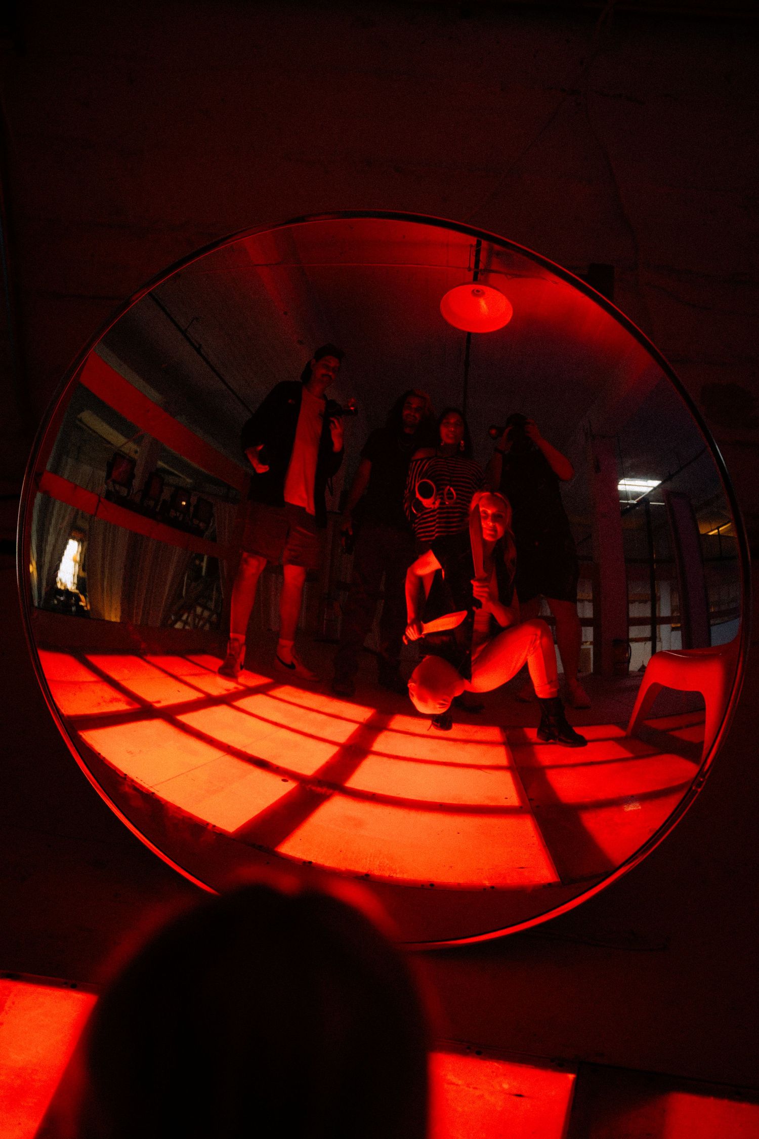 Red-lit fisheye lens captures silhouettes moving through dark atmospheric space.