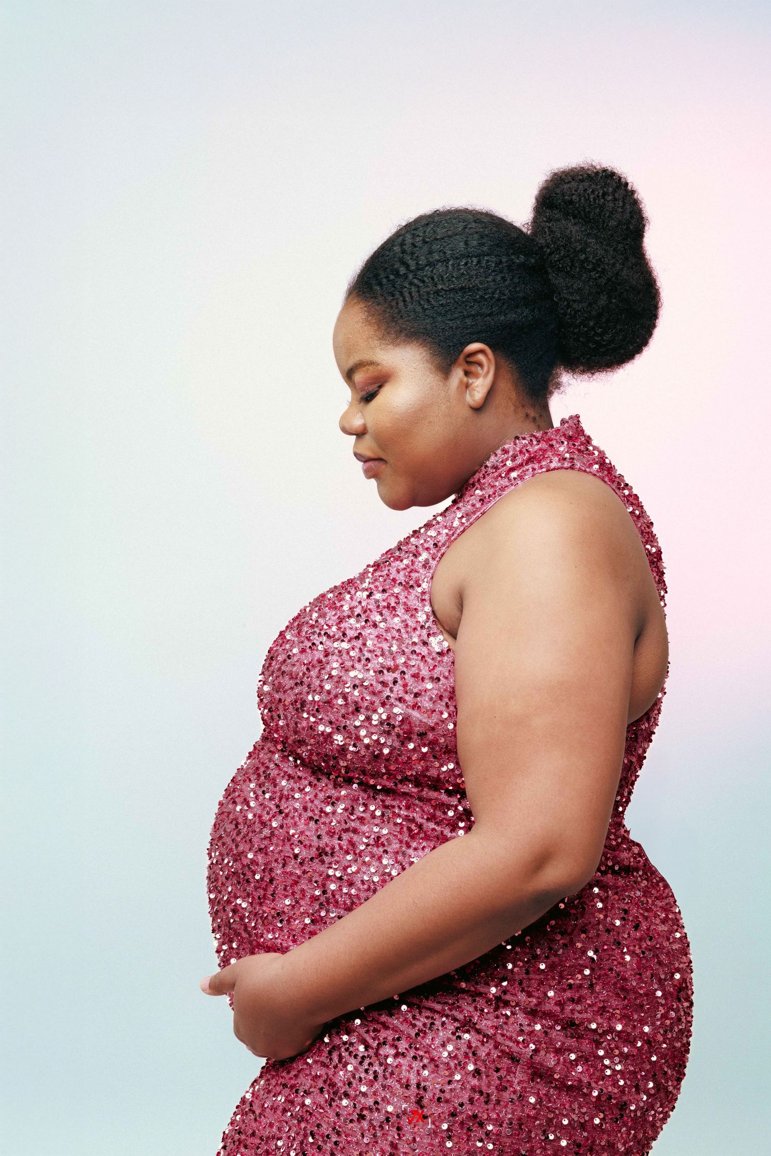 Side profile of a person in a sparkling pink sequined gown posing against a light background.