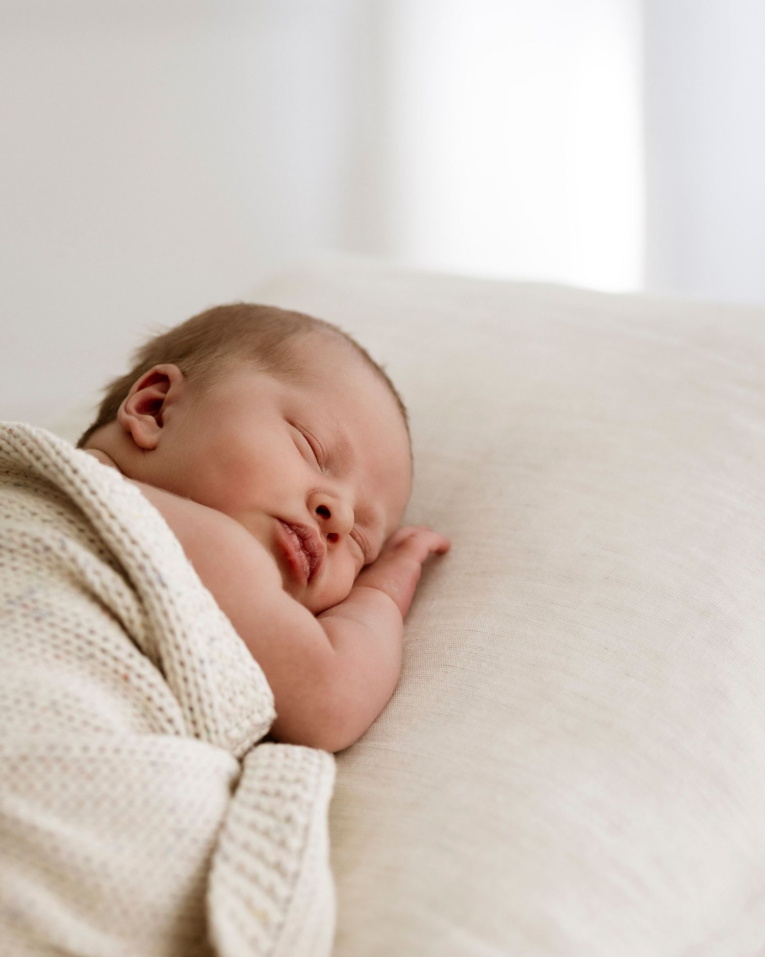 Baby wrapped in neutral blanket, photographed naturally in family’s living room in St Ives