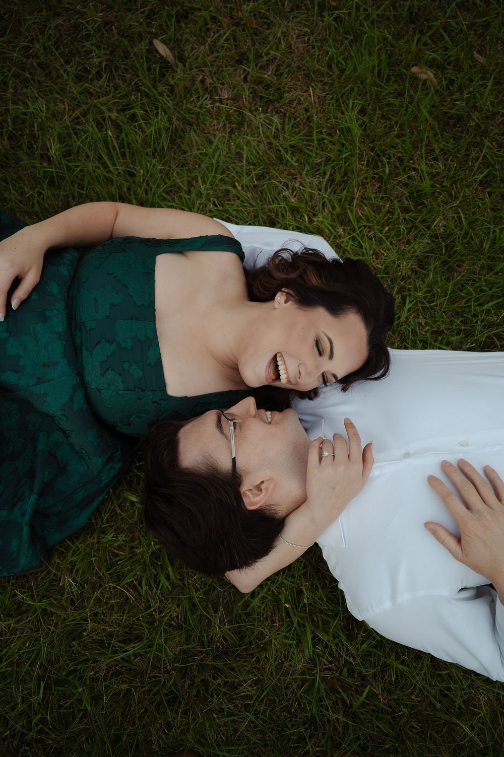 engagement couple laughing laying in grass