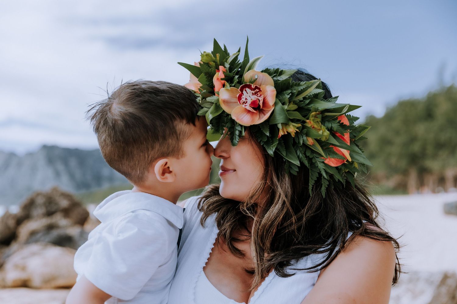Intimate beach photoshoot with tropical flowers and mountain backdrop in Hawaii.