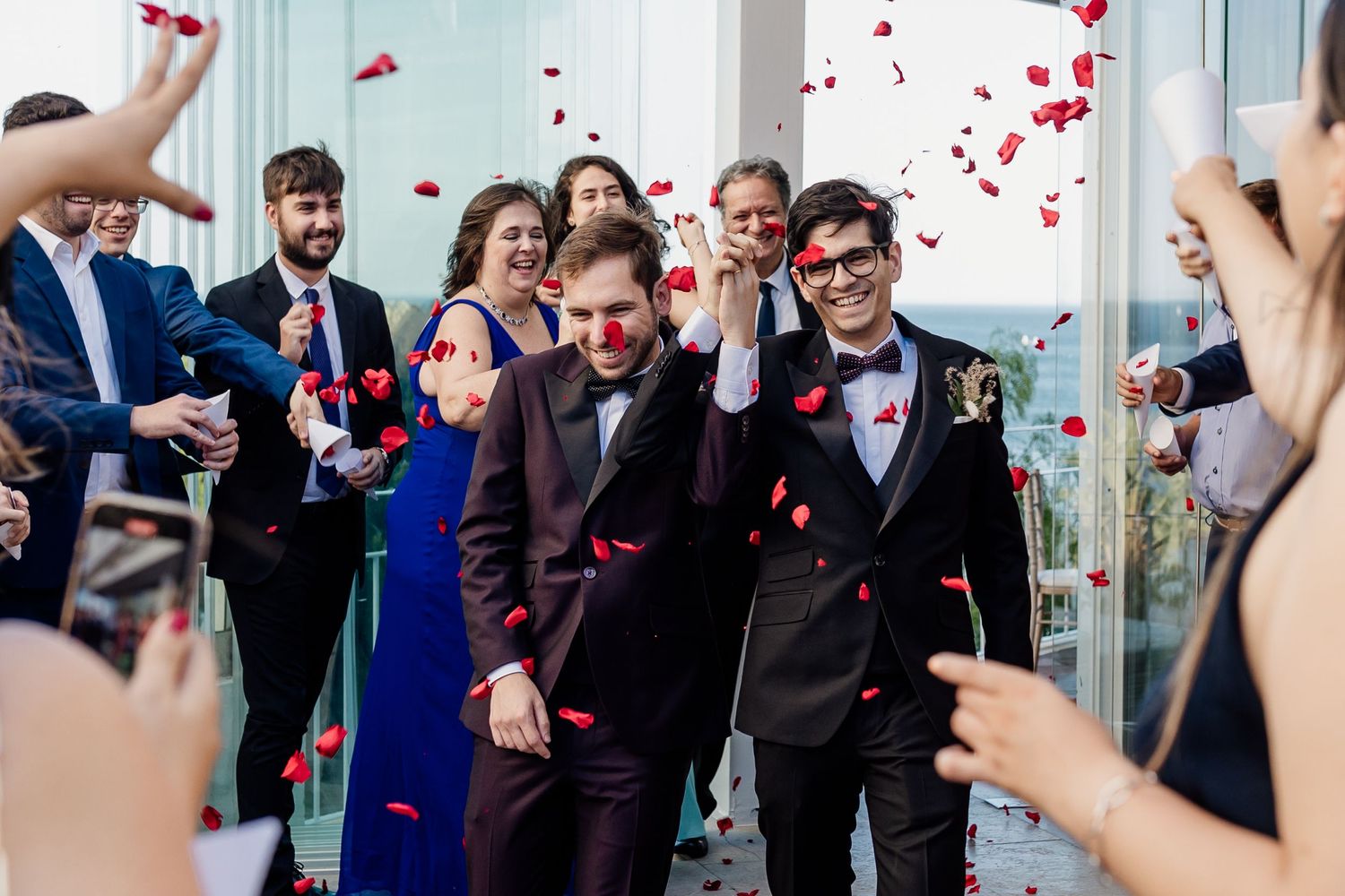 Wedding celebration with red confetti being thrown at the happy couple exiting ceremony.