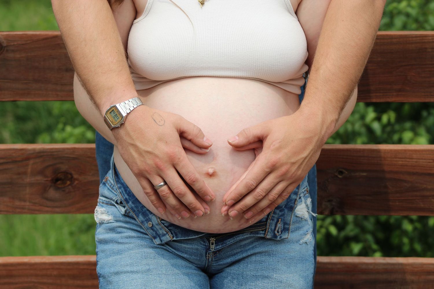 A progression of pregnancy photos showing a growing belly against wooden and natural backgrounds over multiple stages.