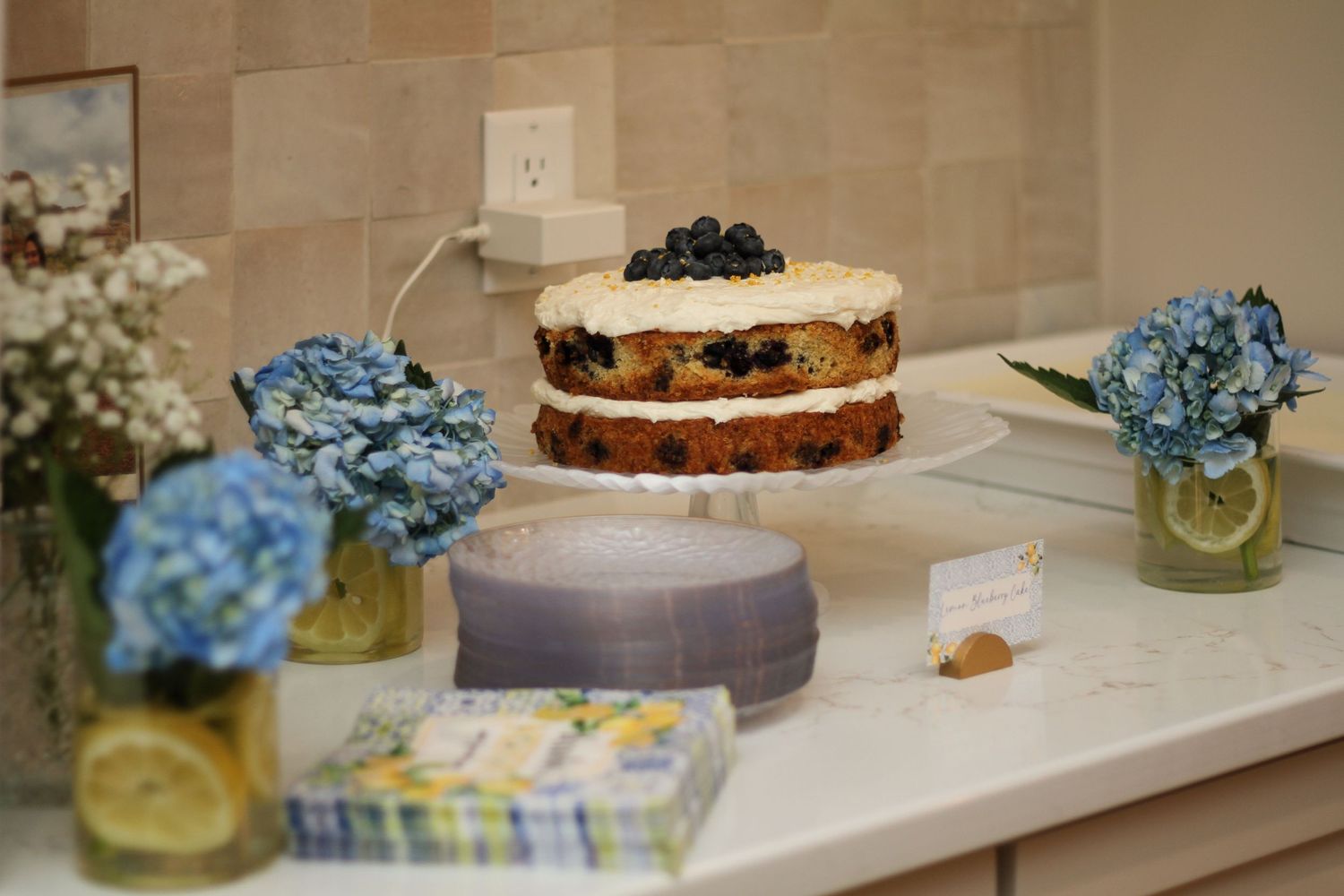 Closeup of blueberry cake slices with cream cheese frosting topped with fresh blueberries in a row.